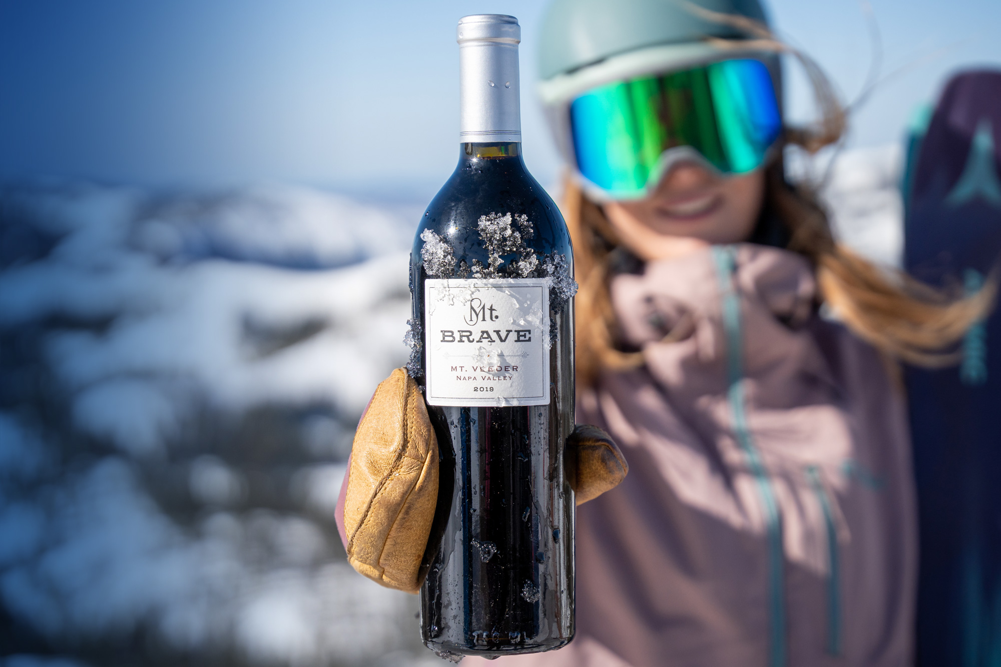 Snowboarder holding a bottle of Mt Brave Wine